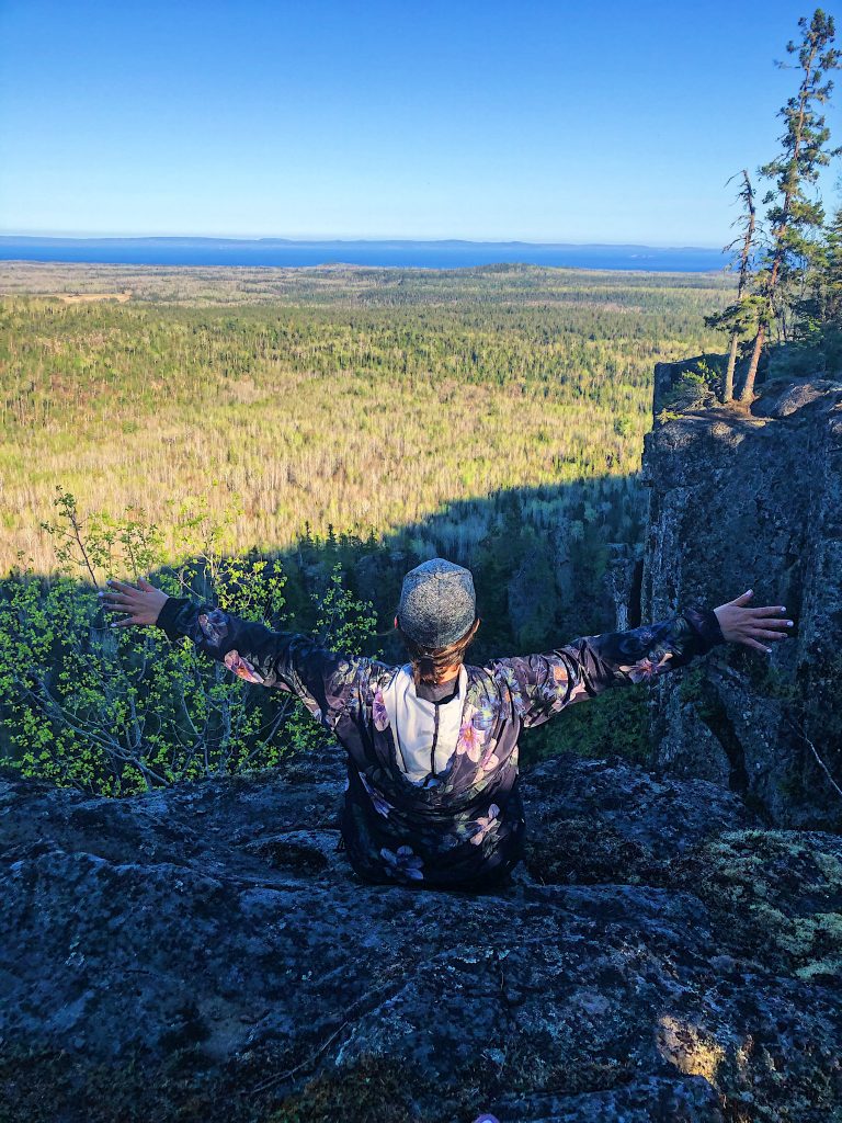 Person overlooking a forest from a rocky cliff
