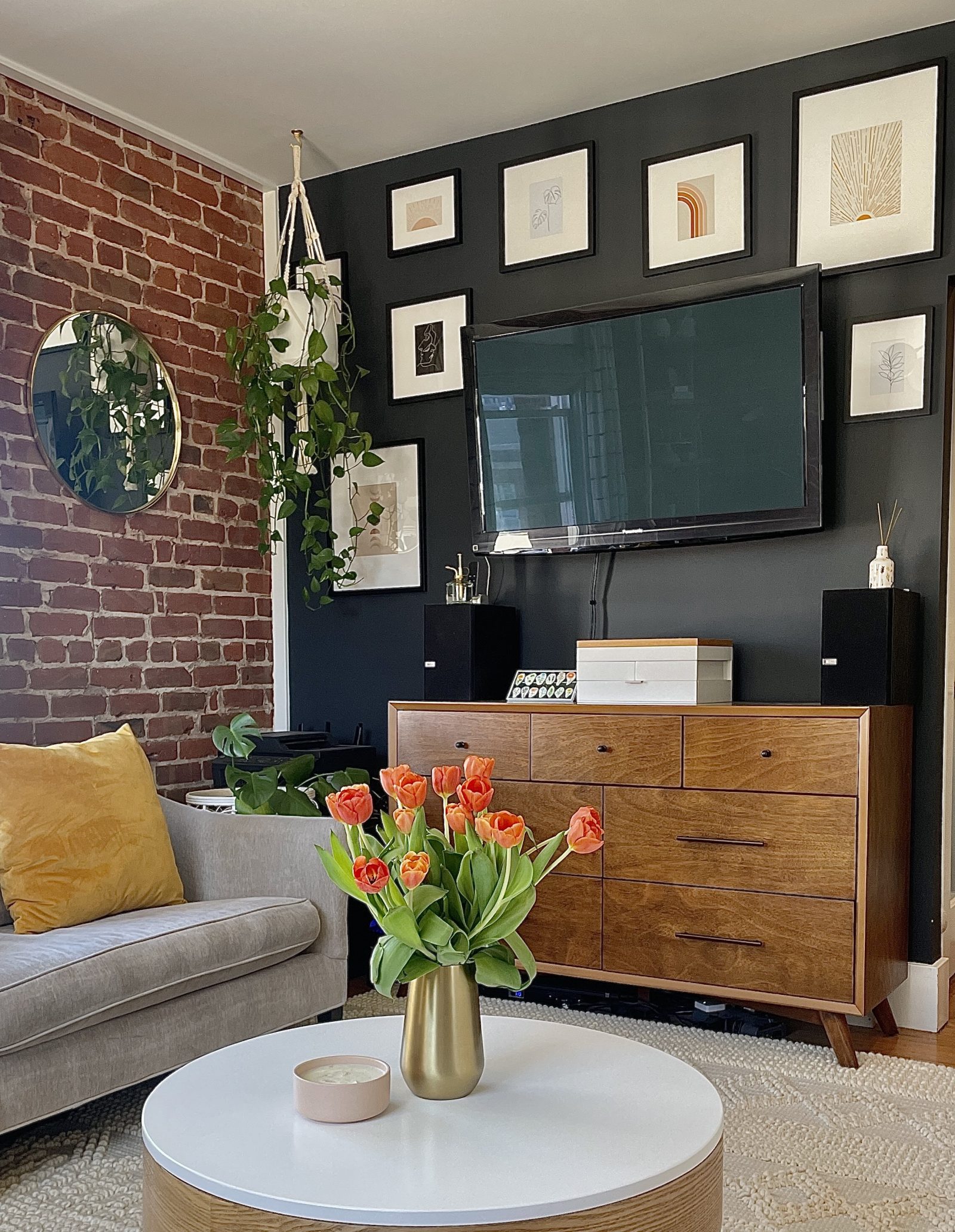 gold vase with red tulips on a modern coffee table overlooking an apartment photo gallery wall